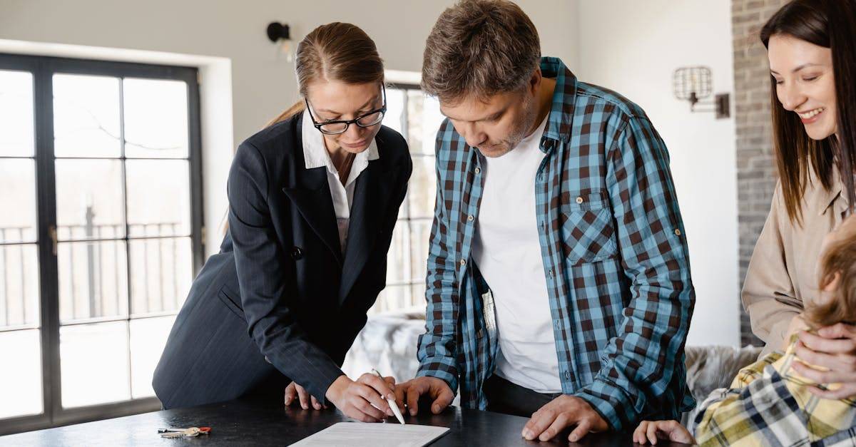 A family reviews real estate documents with an agent, signing for their new home.